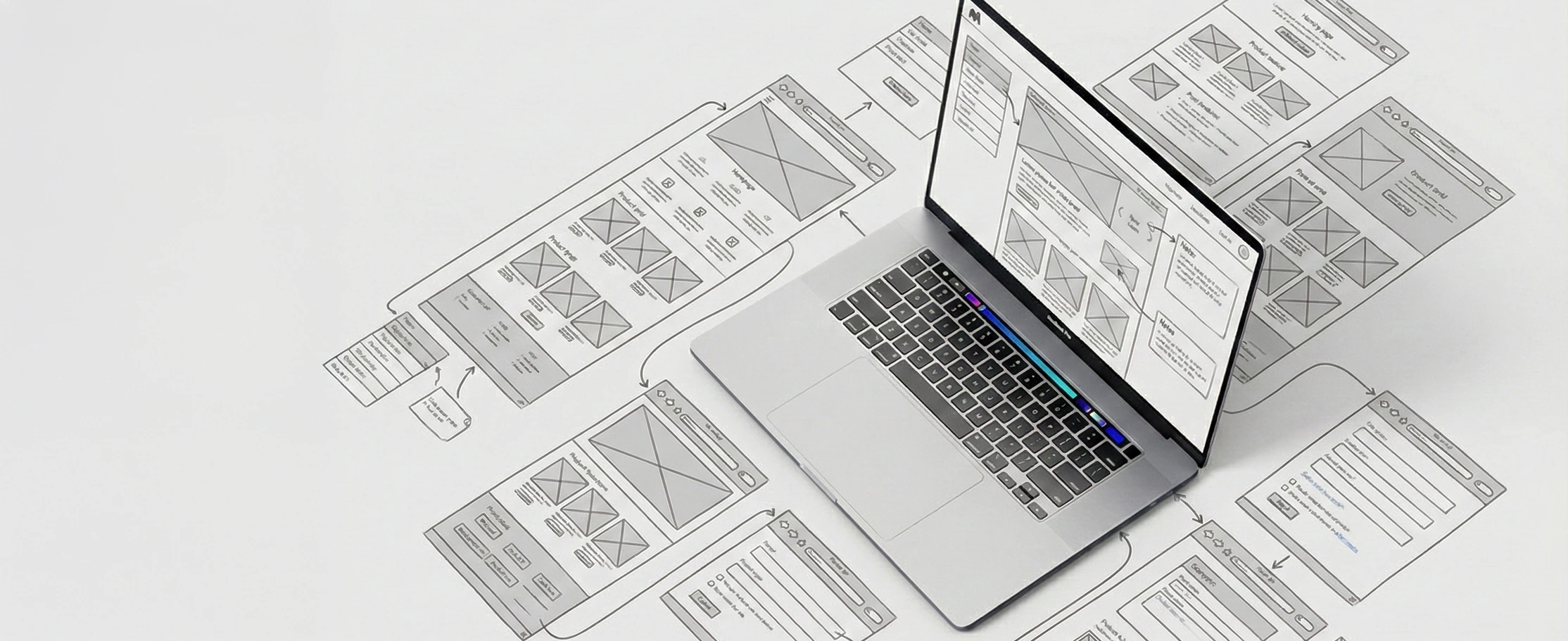 Wireframe systems and UX planning around a laptop workspace.